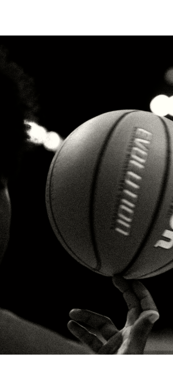 Hooper spinning a basketball on a fingertip in a dark gym